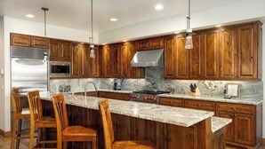 A kitchen with wooden cabinets, a marble countertop, and stainless steel appliances. - Spacious 4BR home in Steamboat Springs, perfect for family getaways! (Steamboat Springs)