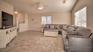 A spacious living room with a sectional sofa, a flat-screen TV, a ceiling fan, and a large window with blinds. - 3 Mi to Beach & Boat Launch: Lake Havasu Home! (Lake Havasu City)