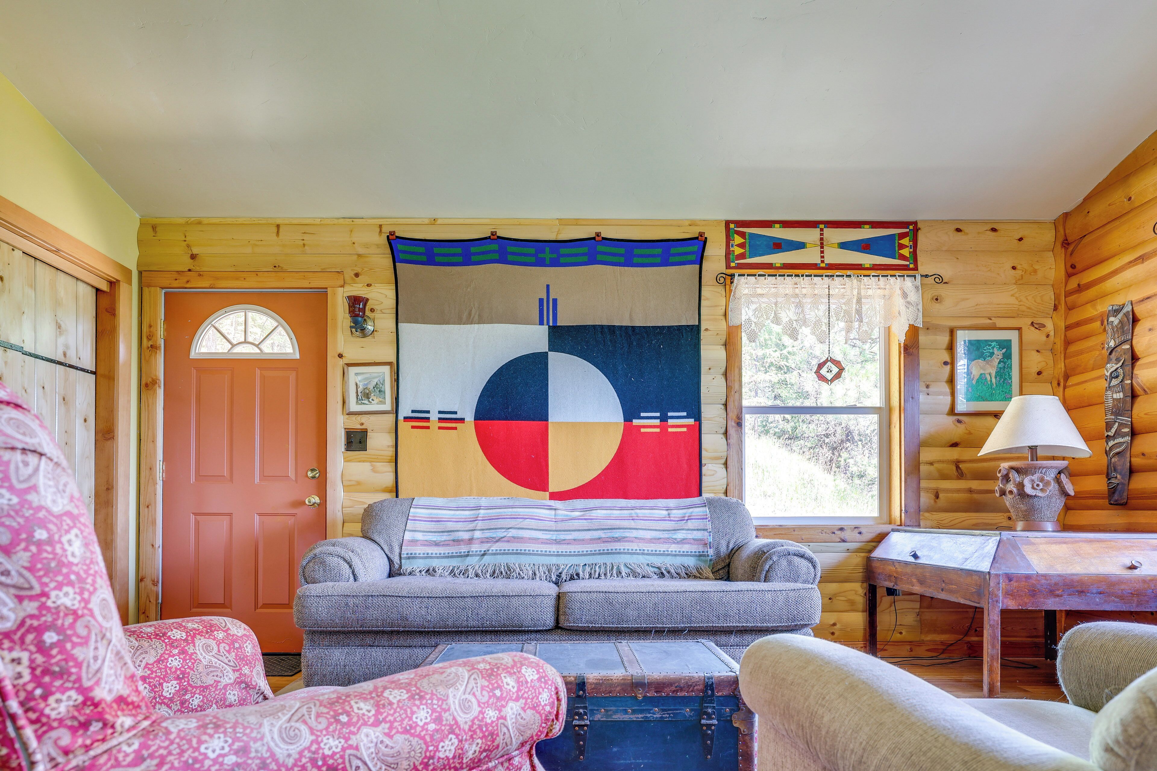 A cozy cabin interior with a couch, a table, and a decorative wall hanging.