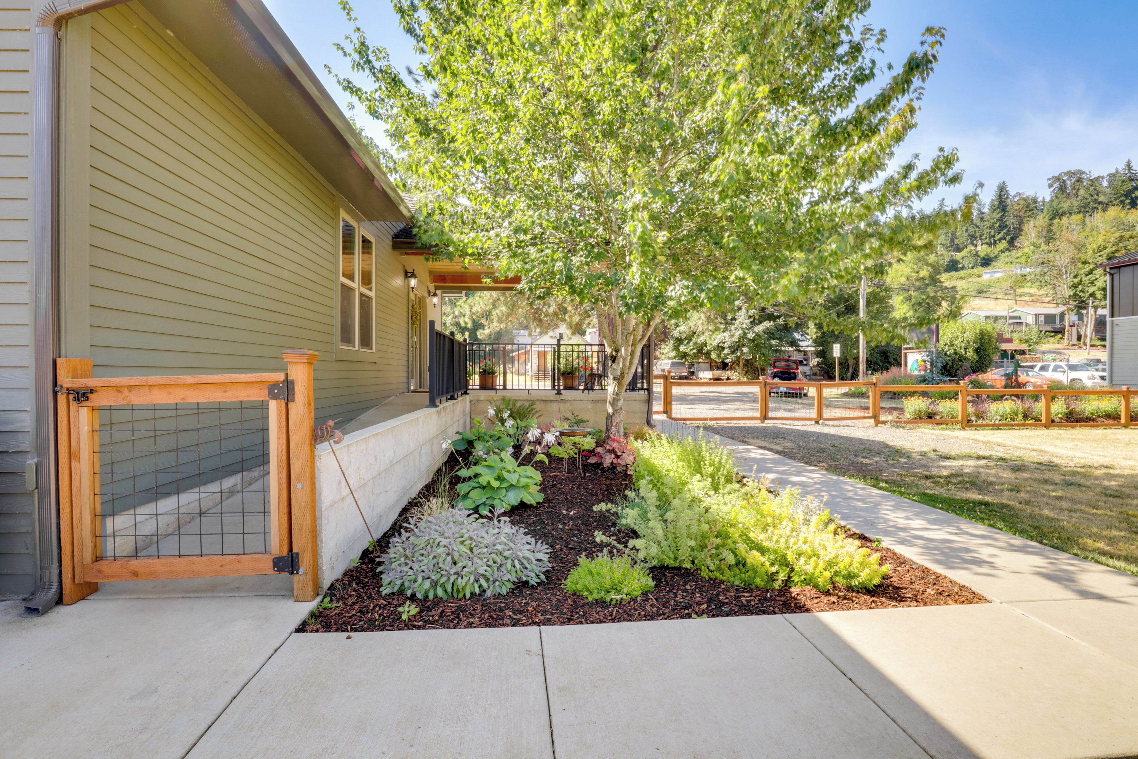 A residential property with a well-maintained garden, a wooden fence, and a clear view of the street.