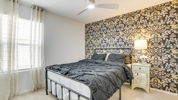 Ein Schlafzimmer mit einem Bett, einem Nachttisch, einer Lampe und einem Deckenventilator.