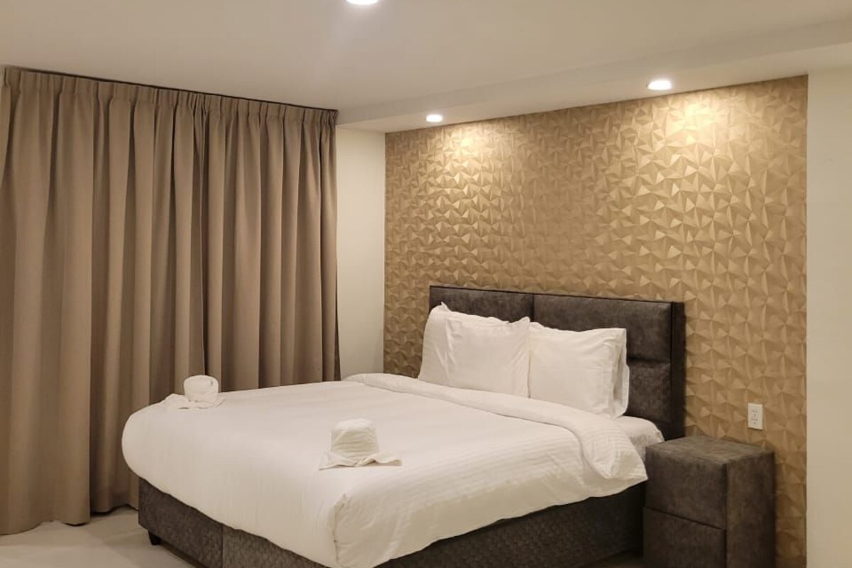 Una habitación de hotel moderna con una cama grande, una mesita de noche y una pared con textura.