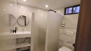 Une salle de bain moderne avec une douche à l’italienne, des toilettes et deux miroirs ronds.