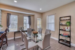 A dining area with a glass-top table, chairs, and a bookshelf with decorative items. - Great Area | 5 bedrooms | Game Room (Baltimore)
