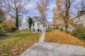 A residential house with a front porch, a staircase leading to the entrance, and a yard with fallen leaves. - Great Area | 5 bedrooms | Game Room (Baltimore)