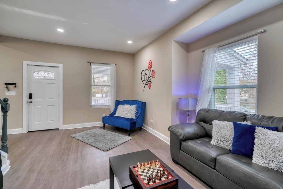 A living room with a chessboard, a blue armchair, a grey sofa, and a white door.