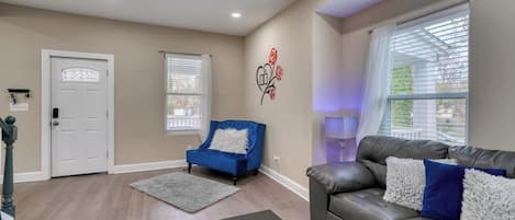 A living room with a chessboard, a blue armchair, a grey sofa, and a white door.
