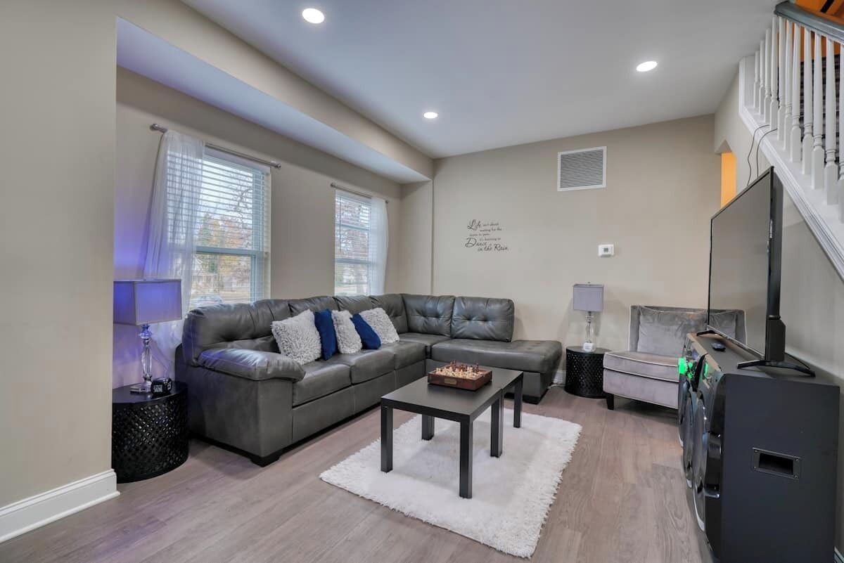 A living room with a sectional sofa, a coffee table, a flat-screen TV, and a staircase.