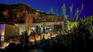 A building with a flat roof, surrounded by cacti and rocks.