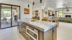 A modern kitchen with a large island, stainless steel appliances, and pendant lighting.