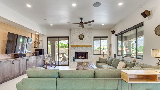 A spacious living area with a fireplace, green sofas, a wooden coffee table, and a television.