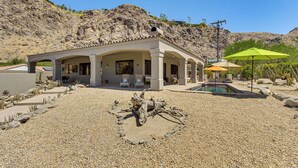 A modern house with a pool, surrounded by a rocky landscape.