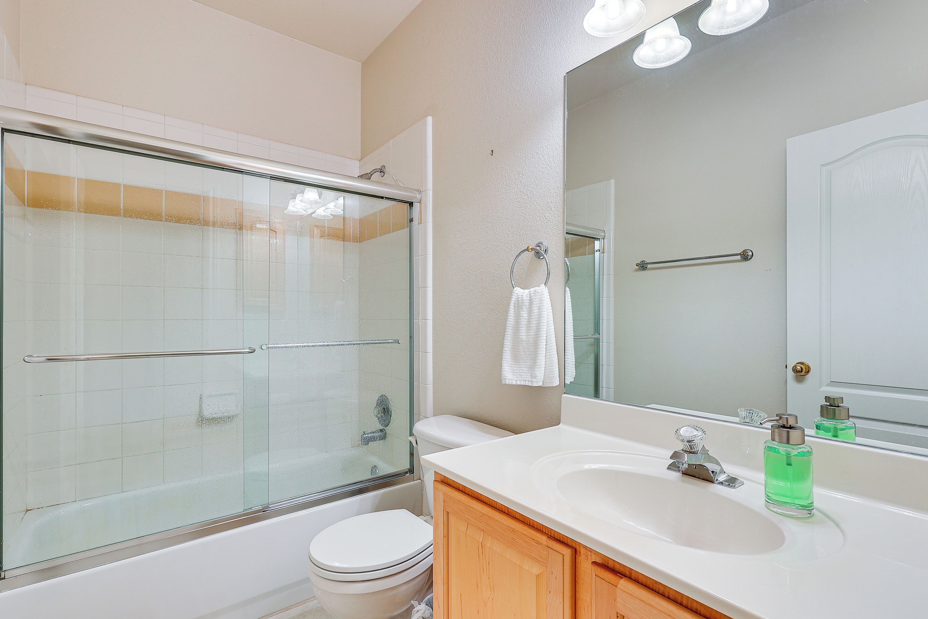 A modern bathroom with a glass-enclosed shower, a white toilet, and a sink with a mirror above it.