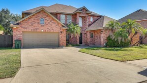 A two-story brick house with a garage, a well-maintained lawn, and palm trees. - Private Theater & Pool: Spacious Mission Home (Mission)