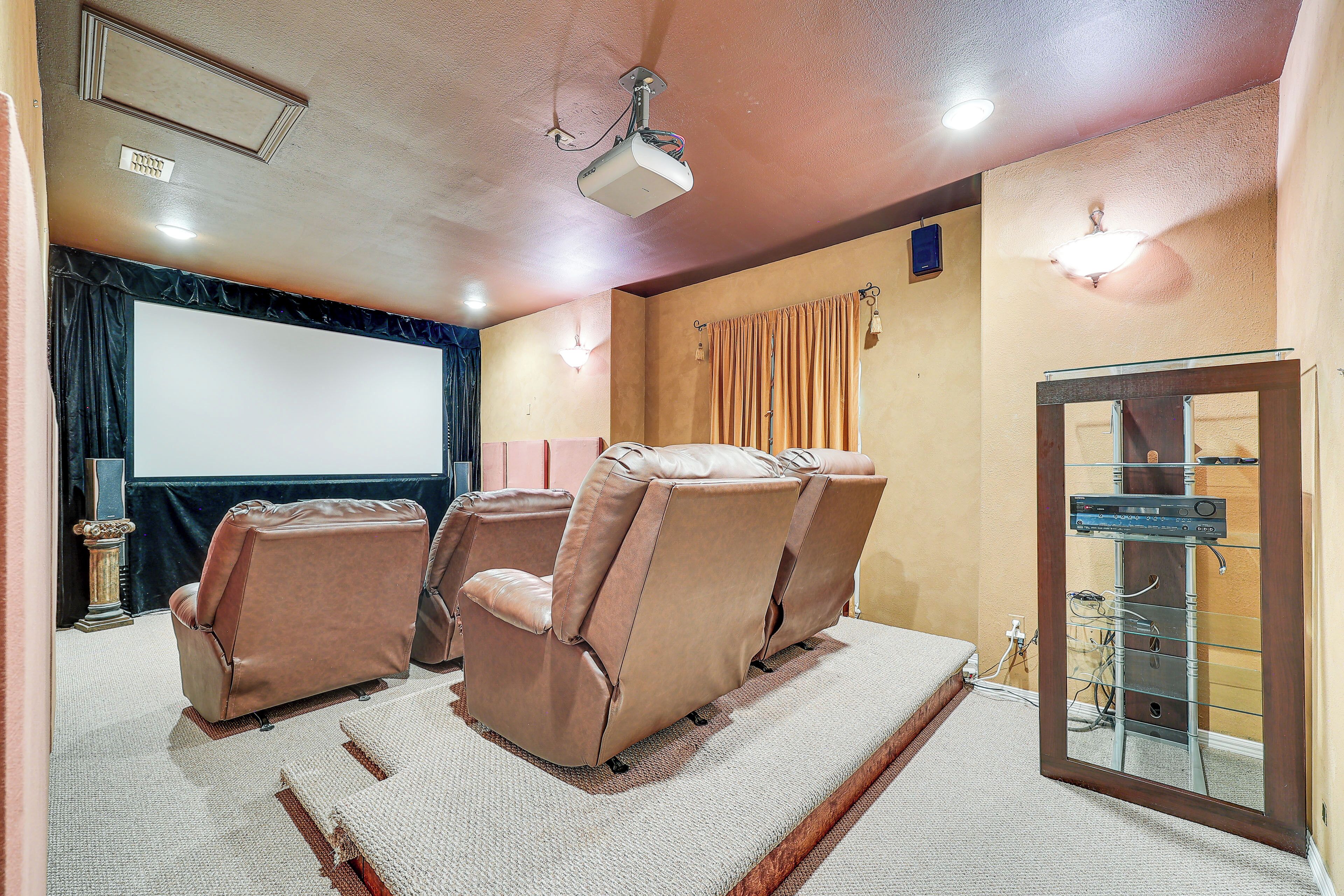 A home theater with reclining chairs, a large screen, and a sound system.