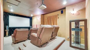 A home theater with reclining chairs, a large screen, and a sound system.