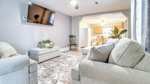 Ein modernes Wohnzimmer mit grauen Sofas, einem Couchtisch und einem großen Flachbildfernseher an der Wand.