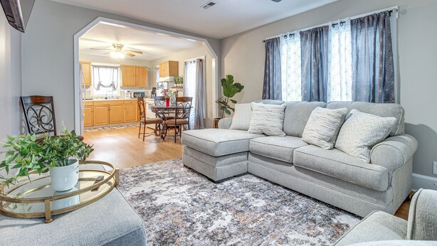 Ein Wohnzimmer mit einem Ecksofa, einem Couchtisch mit Pflanze sowie einem Essbereich mit Tisch und Stühlen.