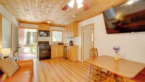 Une cuisine de taille réduite, dotée de meubles en bois, d’une table à manger et d’un ventilateur de plafond.