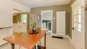 A modern kitchen with white cabinets, a wooden table, and a potted plant. - Home Close to Downtown Frankfort, Walk to Beach! (Frankfort)