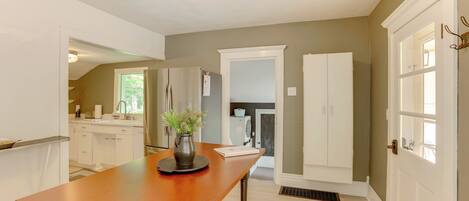A modern kitchen with white cabinets, a wooden table, and a potted plant.