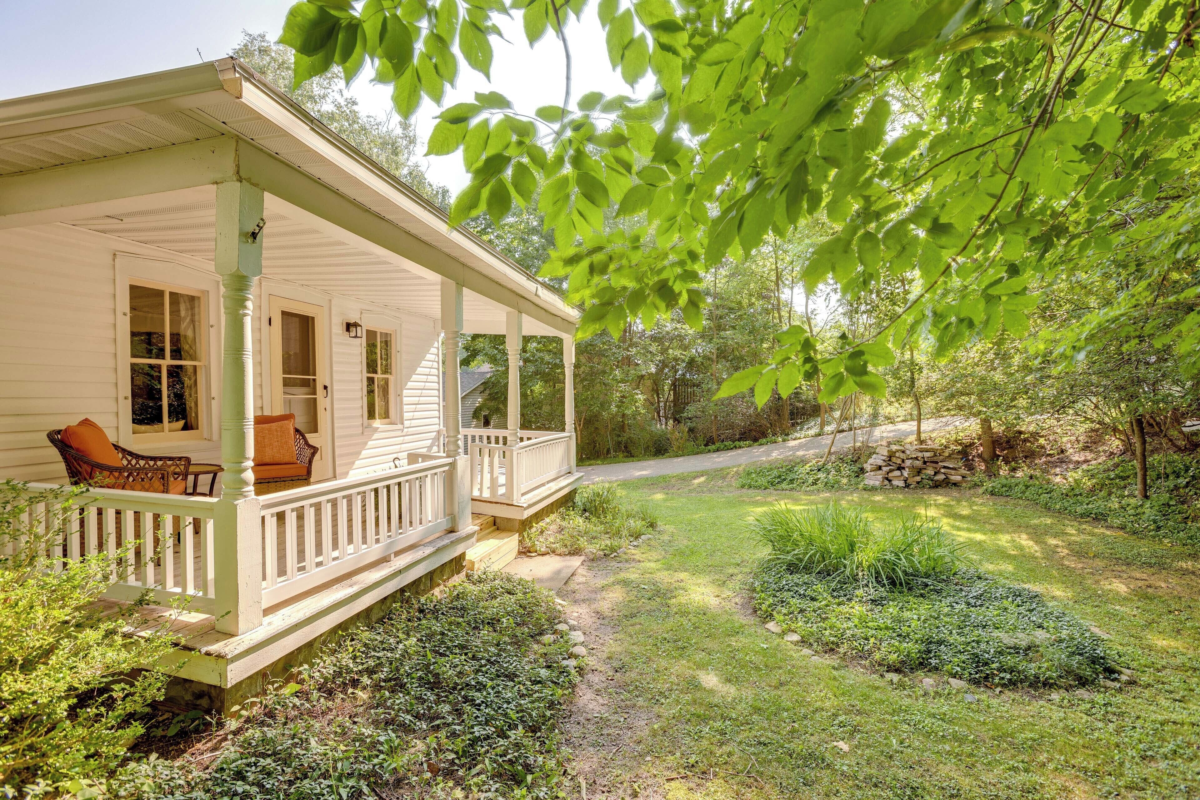 Et hvidt hus med veranda, stol og have.