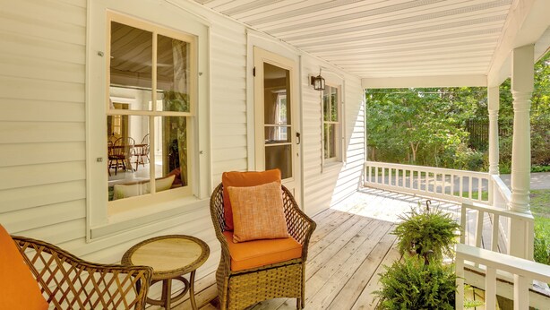 A covered porch with wicker furniture, a small table, and a potted plant. - Home Close to Downtown Frankfort, Walk to Beach! (Frankfort)