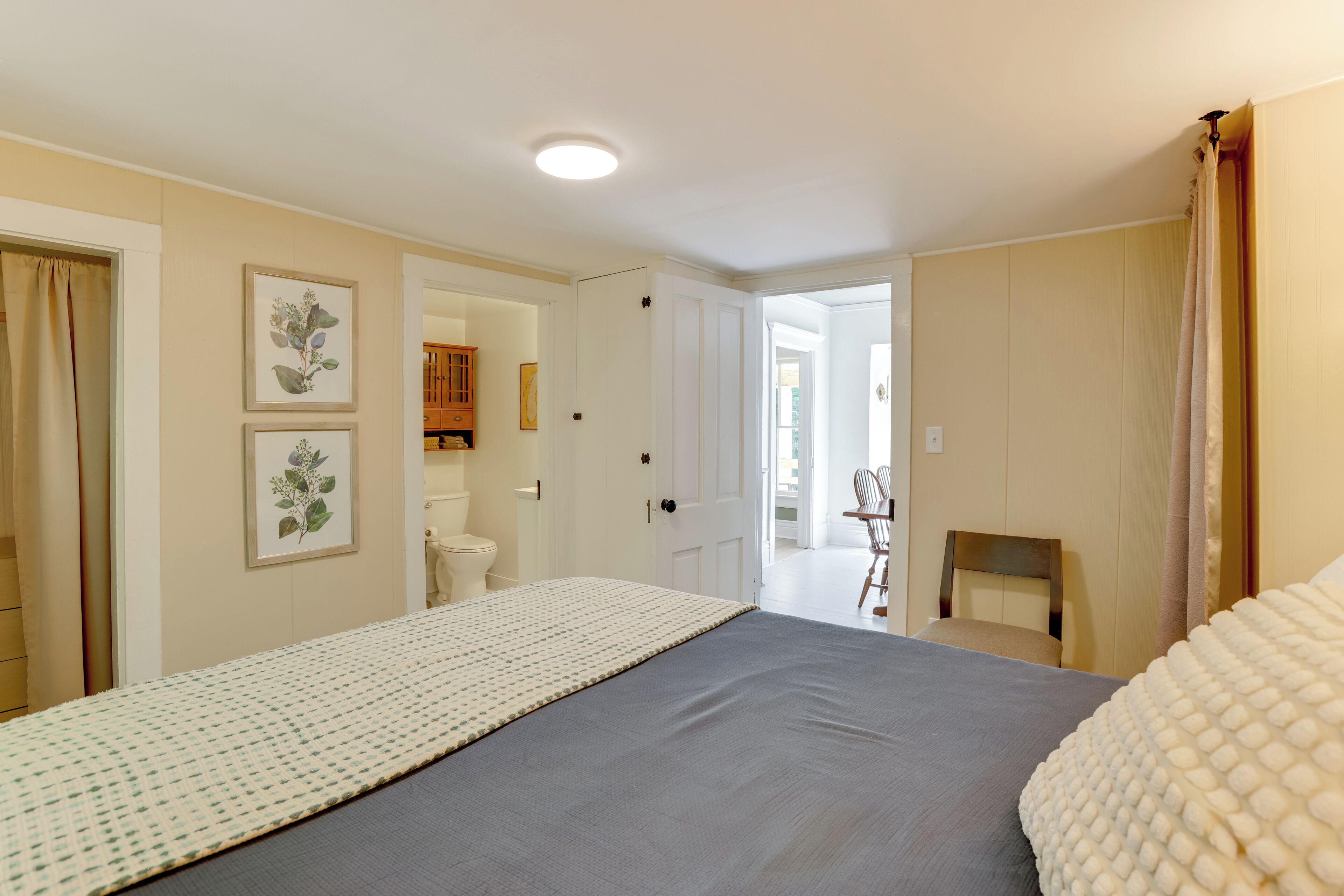 A bedroom with a bed, a chair, and a door leading to another room.