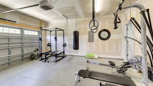 Un gimnasio en casa con una prensa de banca, un soporte para pesas, un saco de boxeo y diverso equipamiento de ejercicio.