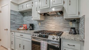 A kitchen with white cabinets, a stainless steel stove, and a tiled backsplash.