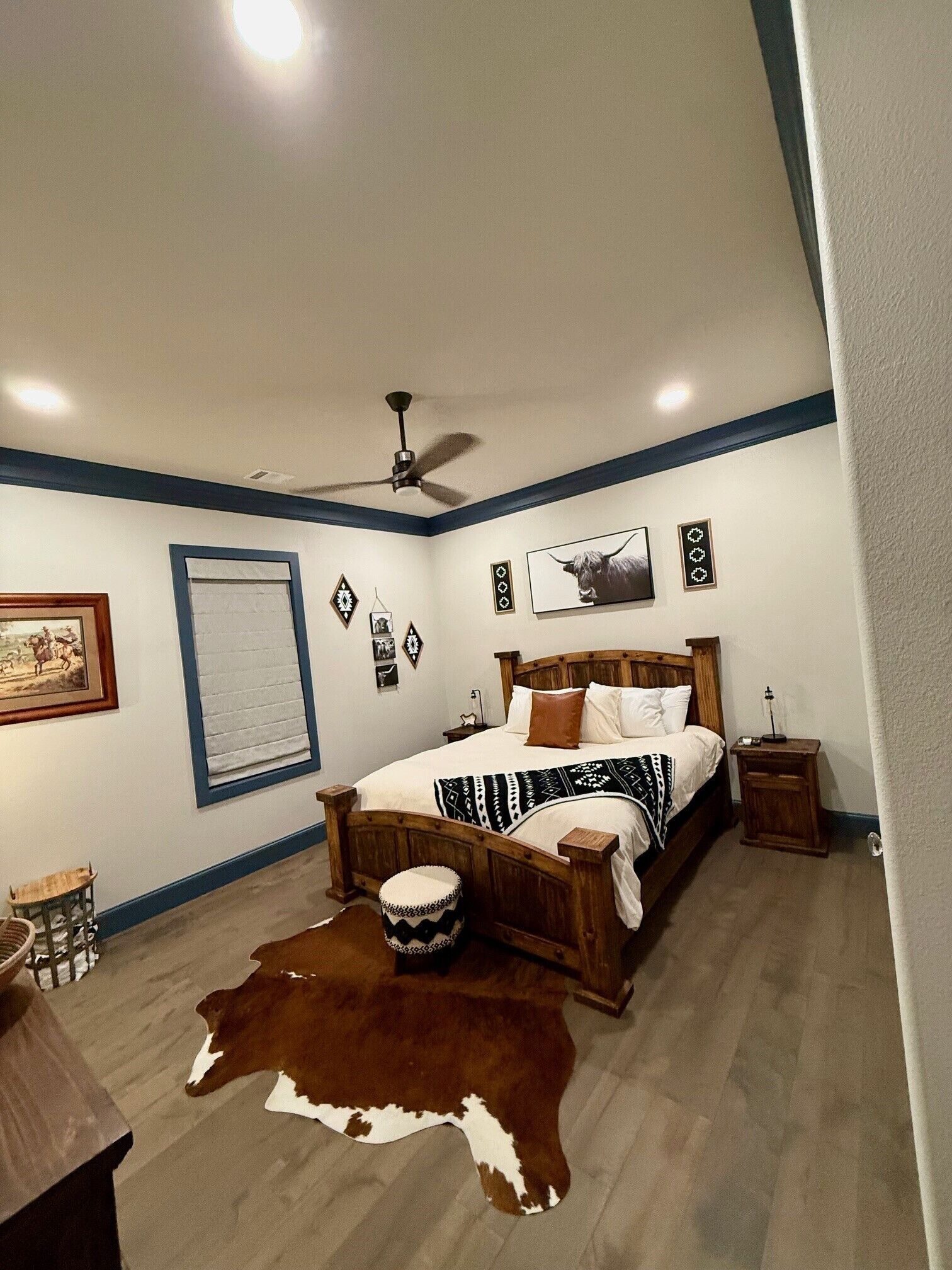 A bedroom with a bed, a ceiling fan, a rug, and a cowhide.