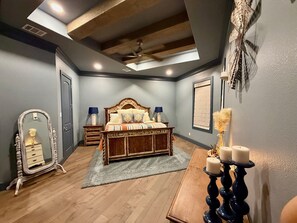 Quarto com cama, penteadeira, espelho, ventilador de teto e luminária na parede.