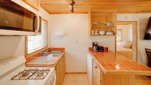 Una cocina compacta con armarios de madera, microondas, cocina a gas y cafetera.