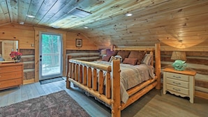 Ein Schlafzimmer einer Holzhütte mit Bett, Schminktisch und Nachttisch.