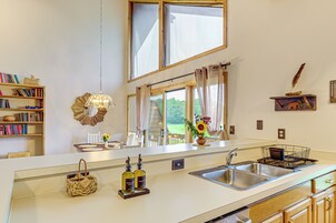A kitchen with a large window, a sink, and a countertop with a vase of flowers.