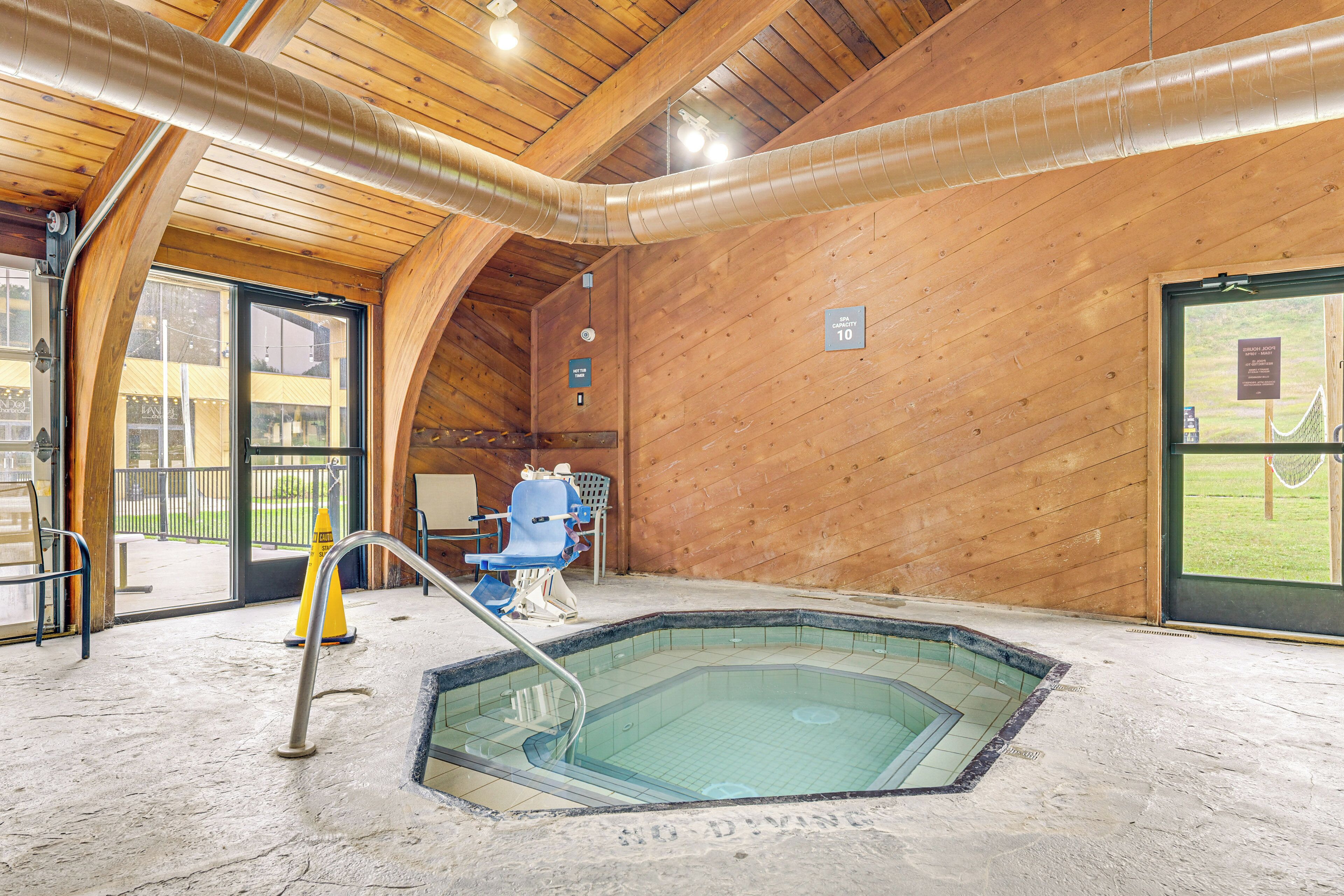 An indoor swimming pool with a wooden interior, a lifeguard chair, and a sign indicating a temperature of 10 degrees Celsius.