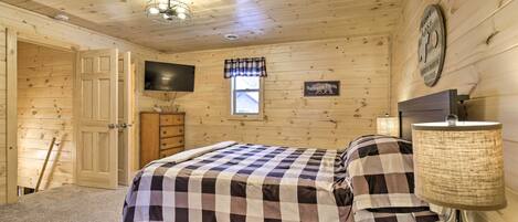 Un dormitorio con paneles de madera, una cama, un televisor, una ventana y un reloj en la pared.