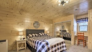 A cozy wooden cabin bedroom with a bed, bedside tables, a chair, and a mirror. - Charming Lost Lake Cabin: Fish, Boat & Hunt! (St Germain)
