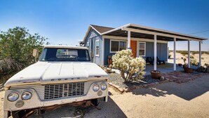 A vintage white truck parked in front of a house with a covered porch and a desert landscape in the background. - Boho Bungalow w/ Hot Tub: 16 Mi to Joshua Tree NP (Twentynine Palms)