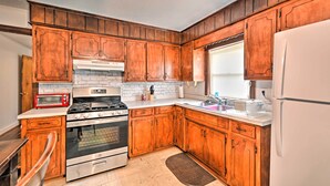 Una cocina con armarios de madera, estufa, horno, refrigerador y una ventana con persianas.