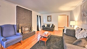 Una sala de estar con chimenea, un sofá, un sillón y una mesa de centro.
