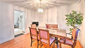 Un comedor con candelabro, mesa de madera y sillas.
