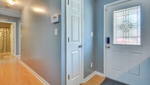 Un pasillo con una puerta blanca, una puerta de cristal con un diseño decorativo y un termostato en la pared.