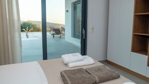 A hotel room with a bed, a view of the outside, and a wooden shelf. - Antiope Retreat (Pitsidia)