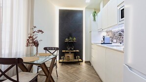 A modern kitchen with white cabinets, a black backsplash, and a wooden herringbone floor. - Bright Apartment in Sevilla Center. Murillo VI (Seville)