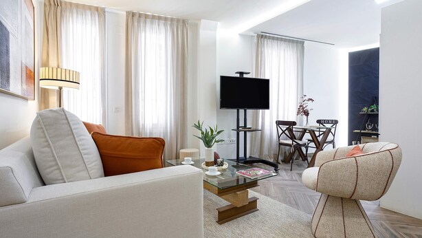 A modern living room with a sofa, a glass coffee table, a TV, and a dining area with a table and chairs. - Bright Apartment in Sevilla Center. Murillo VI (Seville)