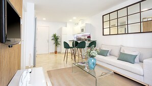 A modern living room with a sofa, a glass coffee table, and a dining area with chairs and a table. - Magnificent Apartment With Perfect Location. Murillo III (Seville)