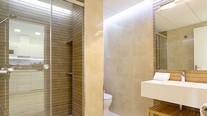 A modern bathroom with a glass-enclosed shower, a white sink, and a wooden vanity. - Magnificent Apartment With Perfect Location. Murillo III (Seville)
