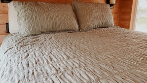 A bed with a textured quilt, wooden walls, and two wall-mounted lamps. - Cozy cabin on Lookout Mountain (Lookout Mountain)