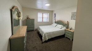 Un dormitorio con cama, cómoda y ventana.